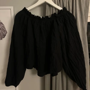 Svart offshoulder blus från Gina Tricot - Säljer en svart blus från Gina Tricot med offshoulder och långa ärmar och någon typ av ”ribbning”