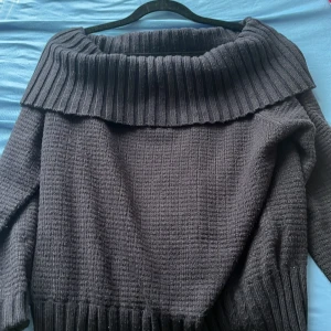 Svart stickad tröja från Dazy - Svart stickad tröja från Dazy i storlek M med bred ribbad krage som kan bäras offshoulder. Tröjan har grovstickad struktur och ribbade muddar vid ärmslut och nederkant. Perfekt för dig som gillar chill och stilren vibe.