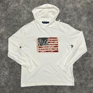 Polo Ralph Lauren USA Flag Hoodie - Tömmer min garderob. Hoodie från Polo Ralph Lauren, den är ganska tunn som en t shirt men ändå skön. Nästan aldrig använd, längden var lite för kort😔🥺
