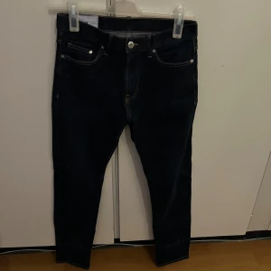  skinny jeans med smal passform - Snygga mörkblå jeans med klassisk femficksdesign och smal passform. Jeansen har kontrastsömmar och silverfärgade nitar och knapp. Perfekta för dig som gillar en tight och stilren look.