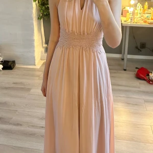 Ljusrosa långklänning - Ljusrosa långklänning med spetsdetalj i midjan och utskärning vid halsen. Perfekt till val🥹💕Bara använd en gång. 