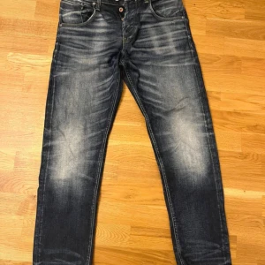 Jack & Jones loose fit jeans blå - Snygga blå jeans från Jack & Jones i loose fit-modell Chris. Jeansen har slitna detaljer och ljusa partier framtill för en cool, avslappnad look. Klassisk femficksdesign och knäppning med knappar. Perfekta för dig som gillar en ledig stil.