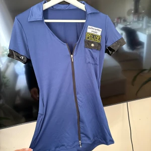 Blå polis klänning med dragkedja - Snygg blå polis dräkt med shorts nedtill som aldrig kommit till användning. Perfekt nu inför halloween! Hatt och handbojor ingår. Köpt för 575.