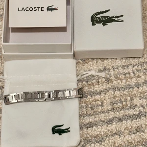 Silverfärgat armband från Lacoste - Helt ny Stilrent armband från Lacoste har inte använt den och boxen och påsen följer med den är helt ny.