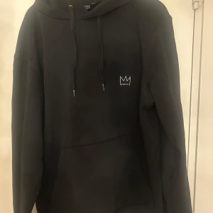 Svart Hov1 hoodie från deras 2025 tour! - Svart hoodie från Hov1 2025 tour,  med broderad krona framtill och stort vitt turnétryck på ryggen. Perfekt för dig som älskar hov1! Säljer då den inte kommer till användning, och de finns inga fler till salu så köp!