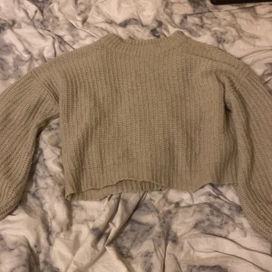 Beige croppad stickad tröja - Mysig beige stickad tröja med croppad passform och långärmade ärmar. Tröjan har en ribbad kant vid hals, ärmslut och nederkant. Perfekt för lager-på-lager under kyliga dagar. storlek l men är liten i storlek.