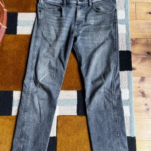 Grå slim fit jeans från BOSS - Säljer ett par grå slim fit jeans från BOSS, modell Delaware. Jeansen har klassisk femficksdesign, normal midja och raka ben. Materialet är mjukt denim i bomull med snygg tvättad look. Perfekta för dig som gillar stilrena och bekväma jeans.