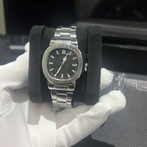  Nautilus silverklocka - Urtavlan har diskreta ränder och tydliga indexmarkeringar. Perfekt för dig som gillar stilren och lyxig design.