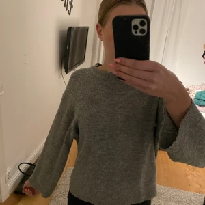 Grå stickad tröja med vida ärmar - Mysig grå stickad tröja med rund halsringning och vida, långa ärmar. Perfekt för lager-på-lager och enkel att matcha med jeans eller kjol. Tröjan har en avslappnad passform och är superbekväm för kyligare dagar. Säljer då den är lite kort i ärmarna på mig då jag är ganska lång.
