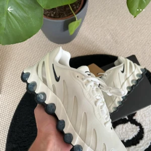 Nike vita sneakers med unik sula - Säljer ett par fräscha vita Nike sneakers med cool, bubblig sula och svart swoosh på sidan. Skorna har snörning och en modern, sportig design som sticker ut. Perfekta för dig som gillar att ha något annorlunda på fötterna.