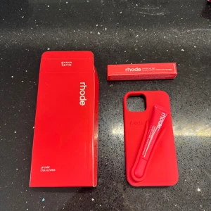 Rhode Peptide Lip Tint Guava Spritz - Rhode Peptide Lip Tint i färgen Guava Spritz, ett läppbalsam med lätt rödrosa ton. Kommer med matchande röd förpackning och ett smart mobilskal där läppbalsamet kan fästas. Perfekt för dig som vill ha återfuktade och snygga läppar on-the-go.