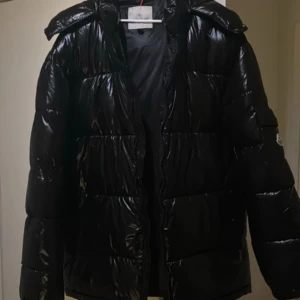 Moncler jacka - -Moncler maya jacka Produktinfo:  – klassisk lyxjacka med glansigt laqué-yttermaterial. 	•	Storlek XL – normal i passform, perfekt för dig som vill ha lite extra utrymme. 	•	Använd väldigt lite, i utmärkt skick: inga fläckar, hål eller slitage. 	•	Fylld med premium gåsdun (90 % dun, 10 % fjädrar) – supervarm men lätt. 	•	Avtagbar huva, högkvalitativa dragkedjor, praktiska inner- och ytterfickor.  💰 Nypris: Nypris hos återförsäljare ligger på cirka 1,535€ - 17 800 kr.