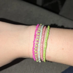 Färgglada pärlarmband i pastell - Säljer ett set med 5 handgjorda armband av små pärlor i rosa och grönt. Armbanden är elastiska och superlätta att bära, perfekta för att mixa och matcha. De har en söt och lekfull stil som ger en poppig känsla till din outfit.