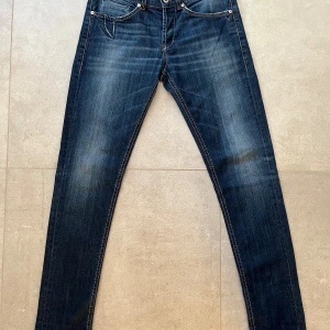 Blå jeans Dondup Georg, storlek 33 - Snygga blå jeans från Dondup, modell Georg, med klassisk femficksdesign och coola detaljer på bakfickorna. Jeansen har en rak passform och är tillverkade i stretchigt denim med 98% bomull och 2% elastan för extra komfort. Perfekt för dig som gillar stilrena och moderna jeans.