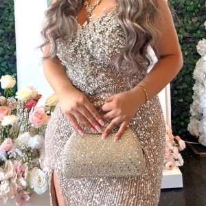 Egen design Champagnefärgad glittrig långklänning - Säljer en magisk champagnefärgad långklänning med glittriga paljetter och pärlor över hela klänningen. Den har en v-ringad urringning, slits på sidan och är figurnära med snygg passform. Perfekt för bal eller fest, med exklusiv känsla och detaljer som verkligen sticker ut. Snören bak. Priset kan diskuteras 