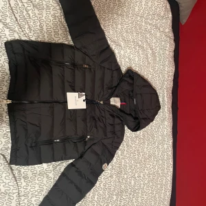 Moncler galion - Billigast på plick - Svart Moncler-dunjacka med huva. Dragkedja framtill med dubbel zip och två fickor som oxå har zip. Perfekt inför vintern! Där loggan sitter kan man öppna/stänga, funkar som liten ficka. Storlek 2 (motsvarar M). Väldigt fräsh jacka, använd bara 1-2 ggr. Moncler triangel + papper finns kvar, loggan går att scanna med NFC (syns på sista bilden). Billigaste Galion på Plick, priset är inte hugget i sten – kan gå ner lite vid snabb affär. Hojta om du undrar nått eller vill se fler bilder!