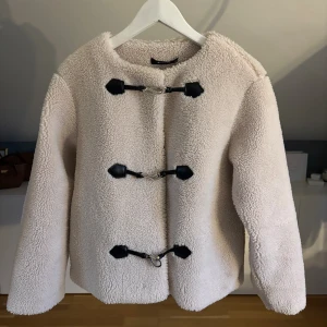 Vit teddyjacka med spänne - Säljer denna snygga vita teddyjacka från Gina tricot med spännen. Den är helt slutsåld på hemsidan och köptes för 799kr. Använd några gånger, men väldigt bra skick!