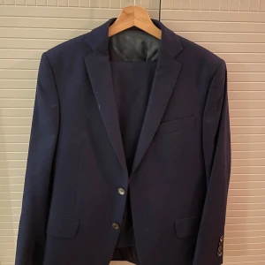 Oscar Jacobsson kostym - En snygg, stilren och tidslös mörkblå kostym ifrån Oscar Jacobsson, den är topp kvalite och är 100% wool. Priset är ej hugg i sten kan gå ner k pris vid snabb affär!! Hör av dig ifall du har frågor