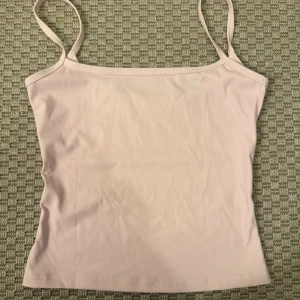 Ljusrosa linnetopp med smala axelband - Aldrig använt. Säljer en enkel och stilren ljusrosa linnetopp med smala axelband. Toppen har en rak och tight passform, perfekt för att matcha med jeans eller kjol. Materialet känns mjukt och lätt mot huden, vilket gör den skön att bära under varma dagar.