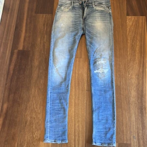 Replay Anbass ljusblå skinny jeans w32 L34 - Säljer ett par Replay Anbass jeans i ljusblå tvätt med slitningar och skinny passform. Klassisk femficksmodell med läderpatch bak och snygga detaljer på bakfickorna. Jeansen är tillverkade i stretchig denim för extra komfort.