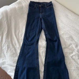 Bootcut jeans från Bubbleroom, blå - Snygga mörkblå bootcut jeans från Bubbleroom i storlek 34. Modellen är högmidjad med klassisk femficksdesign och dragkedja fram. Jeansen har en smickrande passform och är tillverkade i stretchigt denim-material för extra komfort.