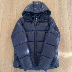 Marinblå pufferjacka från Save The Duck - Säljer en marinblå pufferjacka från Save The Duck i storlek M. Frakt från 59 sek
