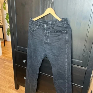 Svarta relaxed jeans Jack & Jones - Säljer ett par svarta jeans från Jack & Jones i relaxed fit-modellen Chris. Jeansen har klassisk femficksdesign, knäppning med knappar och är tillverkade i mjukt denimtyg. Perfekta för dig som gillar en lite lösare passform och stilren look.