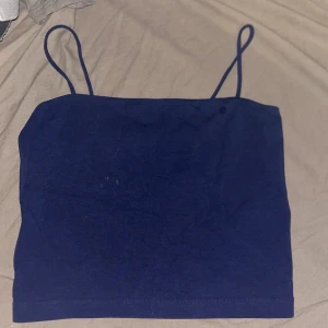 Mörkblå linnetopp från Gina Tricot - Enkel och stilren mörkblå linnetopp från Gina Tricot med tunna axelband. Toppen är rak i modellen och tillverkad i mjuk bomull, perfekt för varma dagar eller att styla lager på lager.