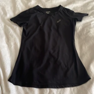 Svart träningst-shirt från Asics XS - Svart, sportig t-shirt från Asics i storlek XS. Tillverkad i lätt och snabbtorkande syntetmaterial, perfekt för träning. Klassisk passform med korta ärmar och rund hals. Diskret Asics-logga på bröstet för en clean look.