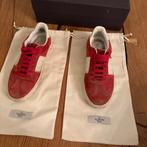 Valentino Rockrunner sneakers röd/vit - Säljer ett par Valentino Rockrunner sneakers i rött och vitt med snygga nitar på hälen. Skorna är i mocka och skinn, har röda snören och en vit detalj på sidan. Kommer med originalpåse och box. Några nitar är borta men man kan beställa nya, kan tänka mig gå ner i pris vid snabb affär. Nypris runt 4000