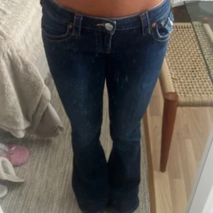 Mörkblå bootcut jeans låg midja - Snygga mörkblå jeans med bootcut-modell och låg midja. Klassisk femficksdesign och tydliga sömmar. Perfekta för dig som gillar en retro vibe och vill ha ett par jeans som sticker ut lite extra.