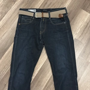 Replay Anbass mörkblå jeans W29 L32 - Snygga mörkblå Replay Anbass jeans med klassisk femficksdesign och kontrastsömmar. Modellen har raka ben och normal passform. Tillverkade i stretchigt jeansmaterial för extra komfort. Perfekta för dig som gillar stilrena och tidlösa jeans.