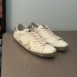 Golden goose super-star  - Hej! Jag säljer ett par Golden Goose Super Star i guld färg och storlek 41. Skorna är i okej skick med vissa tecken på användning, men fungerar och ser fortfarande bra ut. Har även inbyggda högre sulor i innersulan. Tveka inte att höra av dig om du har några frågor eller vill ha fler bilder.