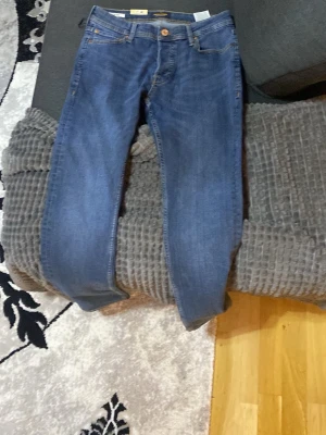 Blå slim jeans från Jack & Jones - Snygga blå jeans från Jack & Jones, modell SLIM GLENN. Jeansen har klassisk femficksdesign, smal passform och är tillverkade i mjukt bomullsjeansmaterial. Perfekta för dig som gillar en modern och stilren look.