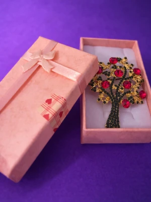 Vacker  – dekorativ brosch  guld pläterade kanter med röda  prismor & strass  - Säljer en Vacker elegant dekorativ brosch i form av ett träd, guldpläterade kanter med  röda kristall stensr i strass. *levereras i en rosa presentask med rosett. Mått CA::7,5CM X4CM Kontakta mig gärna innan köp. *Skickas med PostNord i ett fodrat kuvert . *leveranstid 1-3 vardagar. Mvh Anna 🫶☀️🫶☀️🫶☀️🫶🪅