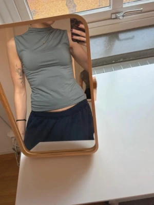 Boatneck topp weekday - Säljer en stilren khaki färg topp från Weekday i storlek S. Toppen är ärmlös med hög hals och har en slim passform. Materialet är mjukt och stretchigt, perfekt för att skapa en clean look. Passar dig som gillar minimalistisk stil.