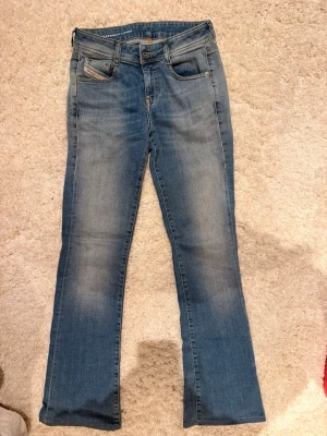 Blå bootcut jeans från Diesel - Säljer ett par klassiska blå jeans från Diesel med bootcut passform. Jeansen har fem fickor, snygga slitningar och en ljus tvätt. Märkespatch bak i midjan och detaljerade sömmar. Skitsnygga. Köpte för 1200kr