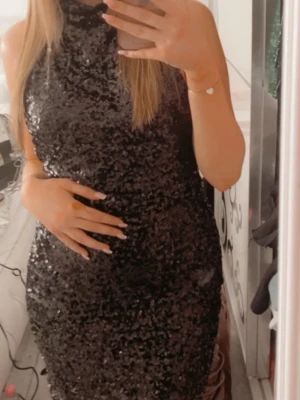 Svart glittrig paljettklänning - Säljer en svart, glittrig kortklänning täckt med paljetter. Klänningen har hög hals och är ärmlös, vilket ger en riktigt snygg och festlig look. Perfekt för dig som vill sticka ut och glänsa på nästa event! Använd en gång på en födelsedags fest! 