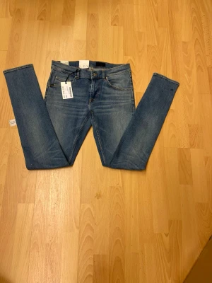 Slimmade  blå jeans  från tiger of sweden W30 L34 - Snygga blå jeans från Tiger of sweden i slim fit med smal passform och smala ben. Klassisk femficksmodell med ljus tvätt och bruna sömmar. Perfekta för dig som gillar en modern och stilren look.
