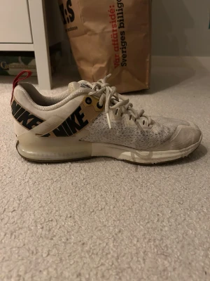 Nike vita sneakers/träningsskor  - Säljer ett par vita Nike training sneakers. Skorna har mesh-överdel för bra andningsförmåga, snörning och en dämpad sula. Perfekta för vardaglig stil men också för gym och jogging.
