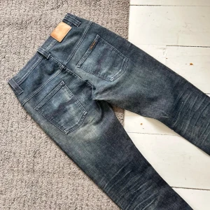 Svarta/Mörkgråa Nudie Tape Ted Jeans - Riktigt unika och snygga Nudie jeans. | W30 L32. | Riktigt fint skick, inga defekter alls förutom en stilren slitning (är ingen defekt). | Tydliga honeycombs & wallet fade. | Längd: 101cm, Midja: 37.5-42cm (Stretch). | Pris ej hugget i sten, skriv vid minsta fundering.
