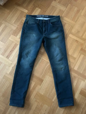 Vintage Genes Black blå jeans - Säljer ett par jeans från Vintage Genes Black med klassisk femficksdesign och snygga slitningar framtill åt min brorsa.  Materialet är mjukt jeans-tyg med stretch för extra komfort. Skriv vid frågor! 