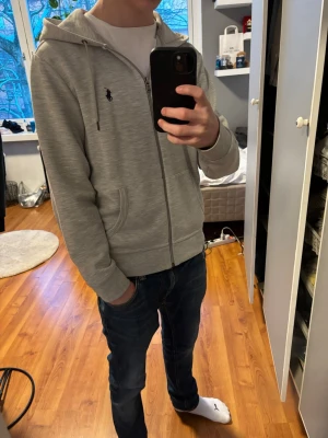 Grå Ralph lauren zip hoodie - Säljer nu denna riktigt feta Polo Ralph lauren zip hoodie i en riktigt schysst grå färg | Storlek XS men passar mer som S (jag är 172 på bilden för referens) | skick 9/10 inga defekter | kan eventuellt gå ner lite i pris vid snabb affär! // Levi 🤩
