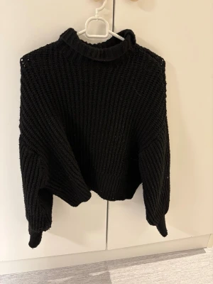 Svart stickad tröja från H&M Divided - Tröjan har en hög krage och är ribbstickad med lång ärm och relaxed fit. Använd enbart fåtal gånger 