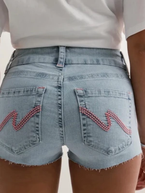 Ljusblå jeansshorts från Nelly - Säljer ett par ljusblå jeansshorts från Nelly med råa kanter och dubbla knappar framtill. Shortsen har hög midja och bakfickor med rosa zigzag-detaljer. Klassisk femficksmodell i mjuk bomullsdenim, perfekta för sommaren.