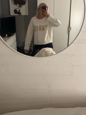 Vit stickad tröja med PARIS-tryck H&M - Supermysig vit stickad tröja från H&M Divided med beige texten PARIS framtill. HELT NY, prislapp kvar❤️skulle säga den sitter s/m