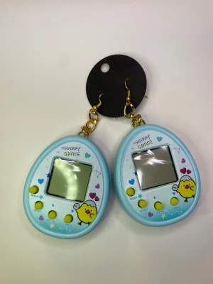 Blå Tamagotchi-örhängen - Det finns tamagotchi örhängen nu som är blåa. Dessa är för barn så barn kan sätta på sig dem och lyssna efter sitt digitala husdjur bättre då kan de ta hand om djuren mer. Örhängen som jag själv gjort. Det finns batterier i båda två.  Örhängen är tyvärr inte allergi testade. Testade ett annat par och inget hände mig dock.