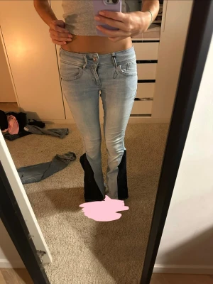 ljusblåa bootcut jeans med marinblåa kilar - säljer ett par ljusblå jeans som ursprungligen var skinny men som jag själv har sytt om till bootcut med svarta paneler nertill. omsömnaden är välgjord och sömmen är rak, stabil och ser bra ut i verkligheten (se bilder). låg/mellanmidja och stretchigt material som sitter snyggt över höfter och ben och faller fint nedtill. använda men i bra skick. säljer eftersom det är för korta på mig tyvärr! unika jeans som verkligen sticker ut – perfekta om du vill ha något ingen annan har💞👍