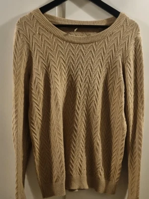Beige stickad tröja från Soyaconcept - Säljer en beige stickad tröja från Soyaconcept med snyggt fiskbensmönster. Tröjan har rund halsringning, långa ärmar och ribbade muddar vid ärmslut och nederkant. Perfekt för lager på lager under kyliga dagar.