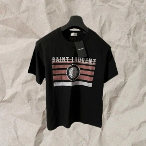 Saint Laurent T shirt - Säljer en svart Saint Laurent t-shirt i helt nytt skick. Aldrig använd. Snygg passform och enkel design med skön logga. Perfekt till både vardags och fest. Hojta till ifall du har frågor/funderingar🙌 den är ute för 695kr, men ifall du börjar följa mig kan jag släppa den för 615kr prick